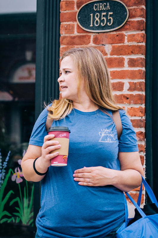 woman holding coffee wearing living my okayest life t-shirt